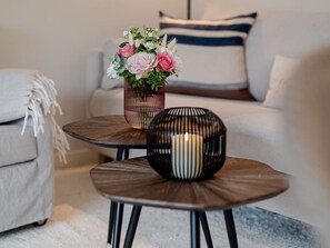 A modern living room with a round coffee table, a vase with flowers, and a spherical candle holder. - Dolles Hüs - Dolles Hüs – Stylish family vacation home with a garden in (Wenningstedt-Braderup (Sylt))