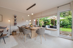 A modern kitchen with a dining area, a sofa, and a view of the garden. - Dolles Hüs - Dolles Hüs – Stylish family vacation home with a garden in (Wenningstedt-Braderup (Sylt))