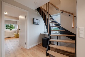 A modern interior with a curved staircase, a view to a balcony, and a door leading to another room. - Dolles Hüs - Dolles Hüs – Stylish family vacation home with a garden in (Wenningstedt-Braderup (Sylt))