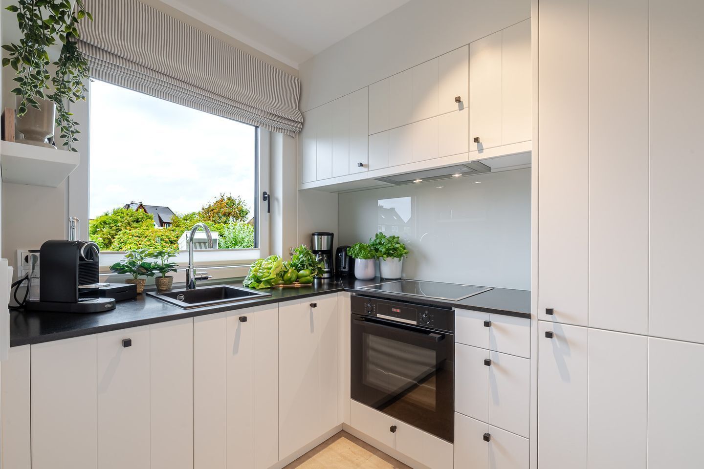 Een koffiezetapparaat/waterkoker, een koelkast, een oven, een kookplaat