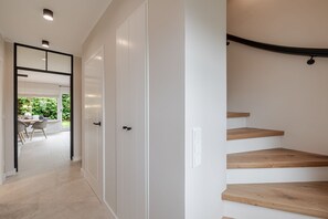 A modern interior with a staircase, a dining area with a table and chairs, and a view of greenery outside. - Dolles Hüs - Dolles Hüs – Stylish family vacation home with a garden in (Wenningstedt-Braderup (Sylt))