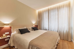 Ein Hotelzimmer mit einem Bett, Nachttischen, einer Lampe und einem großen Fenster mit Vorhängen.