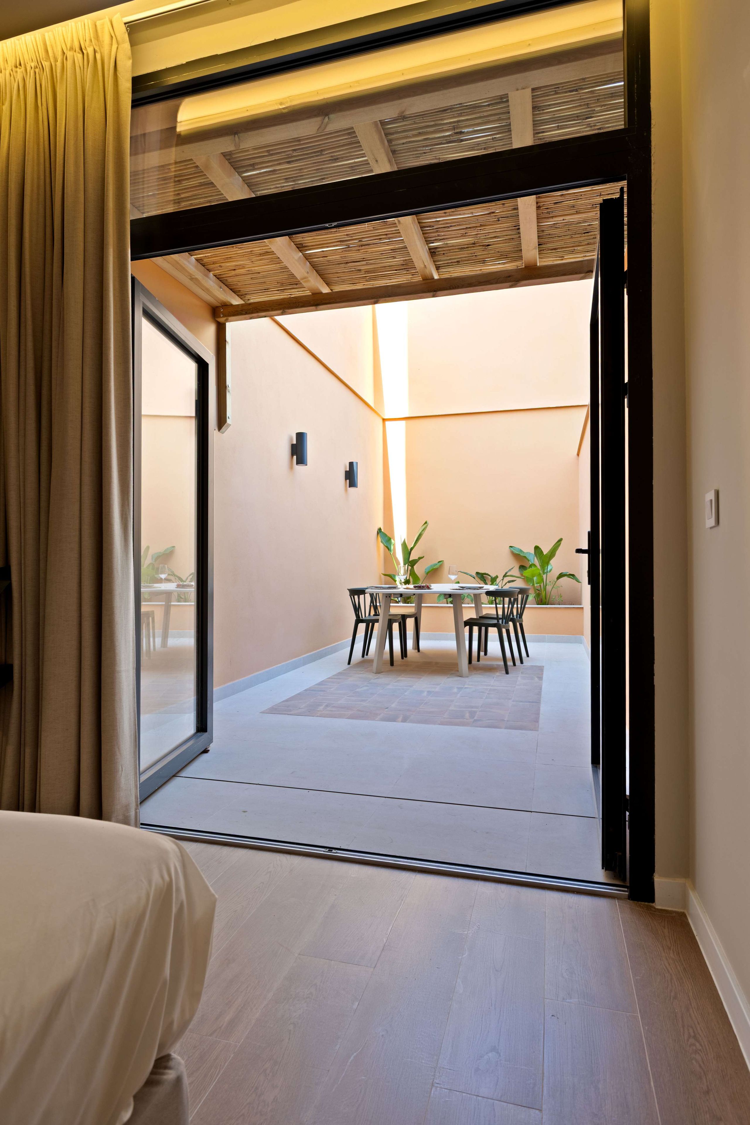 Une chambre d’hôtel dotée d’une porte-fenêtre coulissante donnant sur un espace de restauration extérieur, avec une table et des chaises.