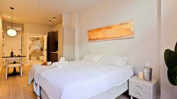 Une chambre d’hôtel moderne avec un grand lit, des tables de chevet, un bureau avec une chaise et un tableau au mur.