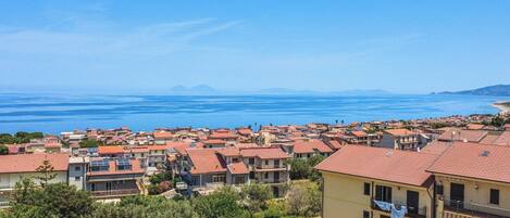 Una zona residencial costera con casas, cielo azul despejado y vista al mar.