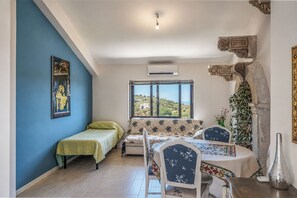 Ein Zimmer mit einem Bett, einem Sofa, einem Esstisch und einem Fenster mit Blick.