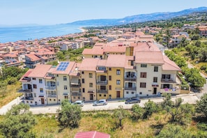 Un edificio residenziale a più piani con balconi, pannelli solari e vista sul mare.