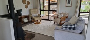A living room with a sofa, armchairs, a fireplace, a television, and a view of the outdoors.