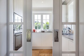Eine moderne Küche mit weißen Schränken, einem großen Fenster und einem Steinboden.
