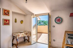 A room with a table, a door leading to a balcony, and decorative plates on the walls. - Panoramics Vacation Home (Acquedolci)