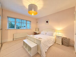 A bedroom with a bed, bedside tables, a lamp, a mirror, a bench, and a window with blinds. - Luxury 4BDR Retreat With Garden and Workspace (Malahide)