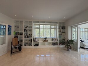 A spacious room with a large built-in bookshelf, a rattan chair, a potted plant, and a sofa. - Luxury 4BDR Retreat With Garden and Workspace (Malahide)