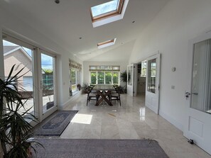 A spacious room with a large dining table, multiple windows, and a skylight. - Luxury 4BDR Retreat With Garden and Workspace (Malahide)