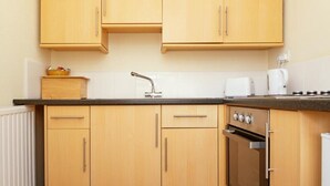 Eine Küche mit Holzschränken, einer Edelstahlspüle, einem Toaster und einem Backofen.