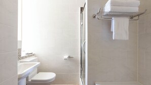 Ein Badezimmer mit Toilette, Waschbecken, Dusche und Handtuchhalter.