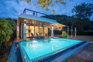 Ein modernes Haus mit Swimmingpool, Sitzgelegenheit im Freien und einer überdachten Terrasse.