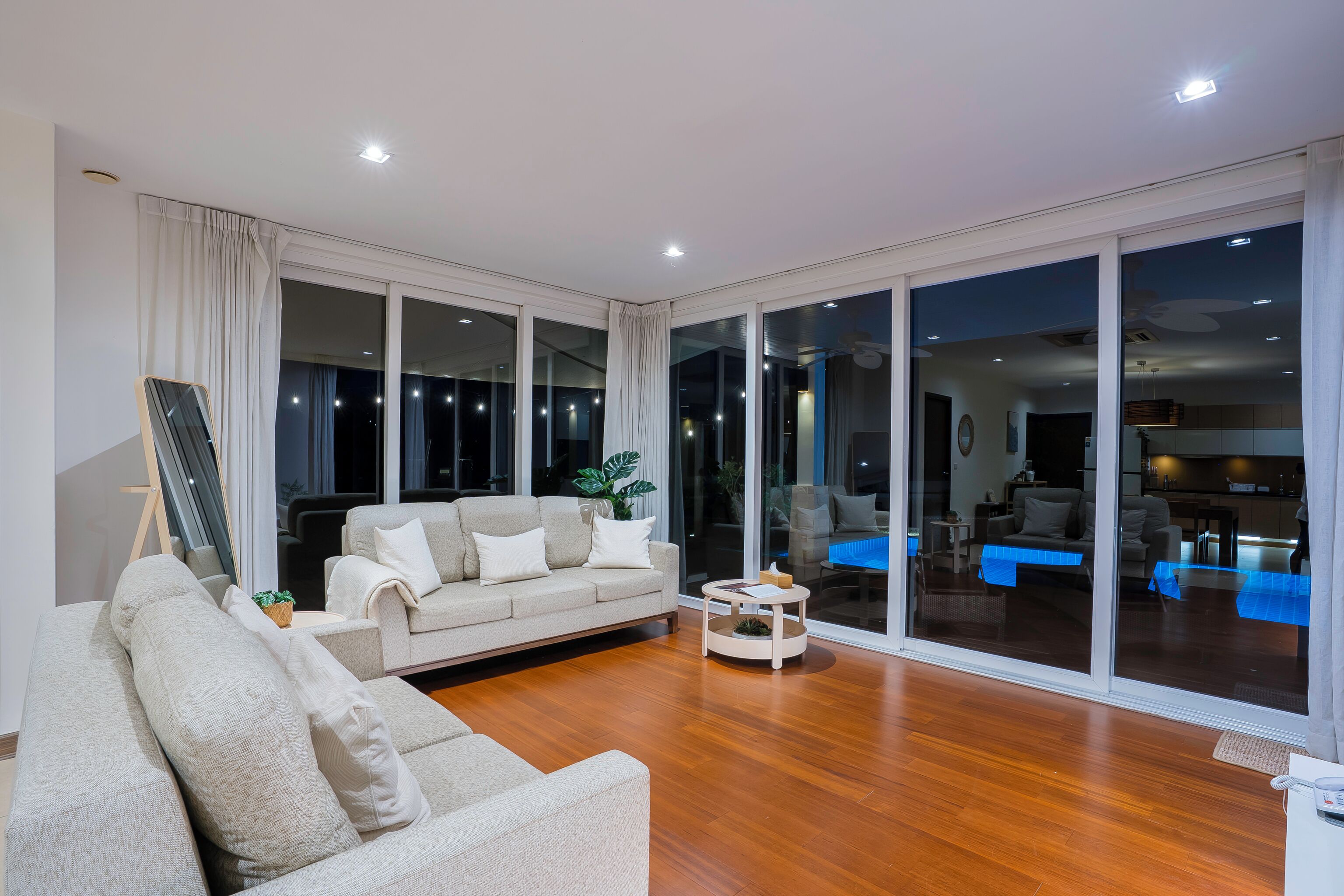 A modern living room with a sofa, a coffee table, and a large sliding glass door leading to a balcony.