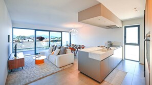 A modern kitchen with a large island, a dining area with a table and chairs, and a sofa. - Design Apartment Gottardo with Views over Lugano (Massagno)