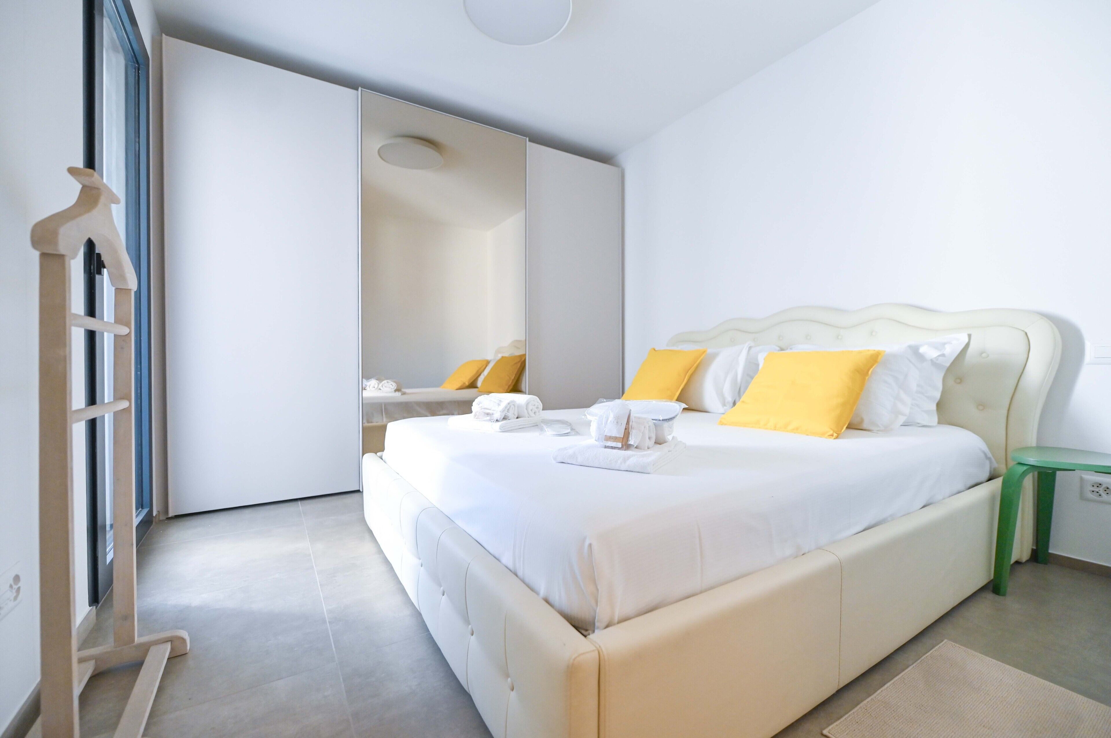 A bedroom with a bed, a green nightstand, a mirror, and a wooden ladder.