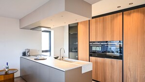 Cozinha moderna com ilha central, eletrodomésticos embutidos e uma janela ampla.