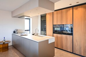 Eine moderne Küche mit einer Kochinsel, integrierten Geräten und einem großen Fenster.