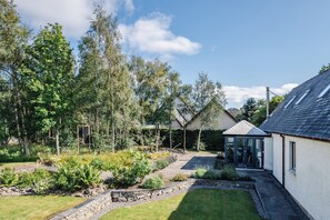 A residential property with a garden, a small shed, and a house with a sloped roof.