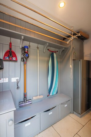 A laundry area with a drying rack, a vacuum cleaner, and a surfboard.