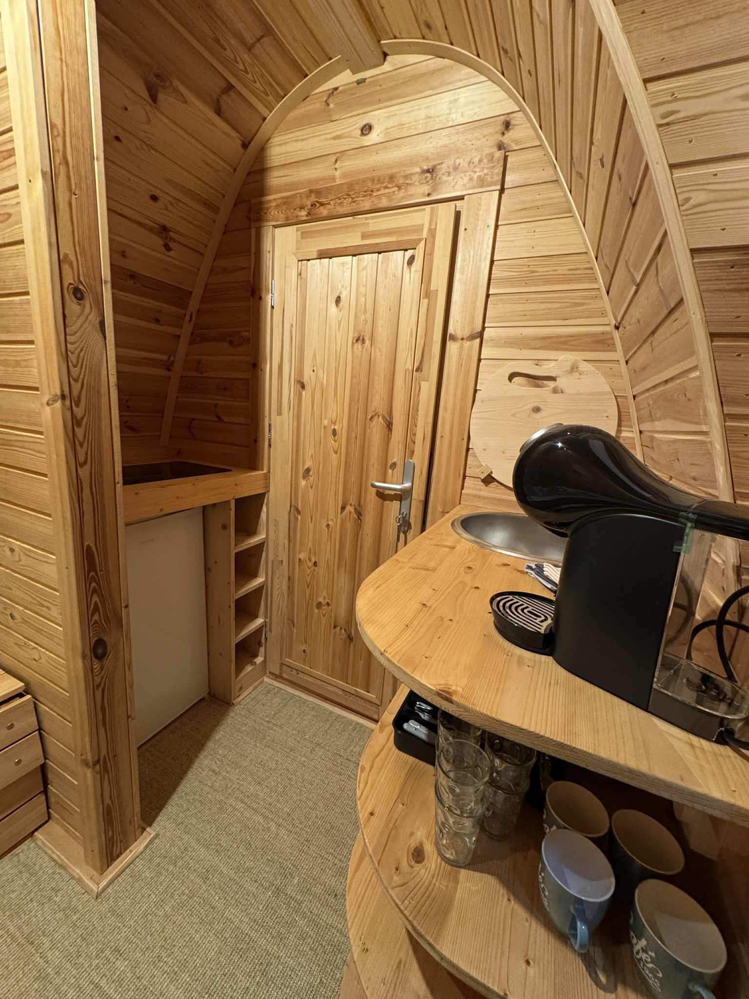 Un intérieur en bois avec un plafond incurvé, un banc intégré, un évier et une machine à café.