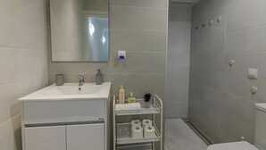 A modern bathroom with a white sink, mirror, and a shower area.
