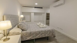 A bedroom with a bed, bedside lamp, and an air conditioning unit on the wall.