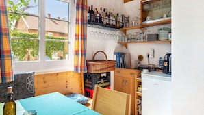 A cozy kitchen with a window, wooden cabinets, and a coffee machine. - Doppelhammer Apartment House (Bad Füssing)