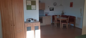 Une cuisine équipée d’un four à micro-ondes, de placards et d’un coin repas avec une table et des chaises.