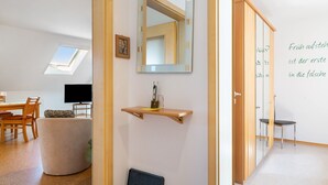 A modern interior with a dining area, a sofa, a TV, a mirror, and a wall with text. - Doppelhammer Apartment House (Bad Füssing)