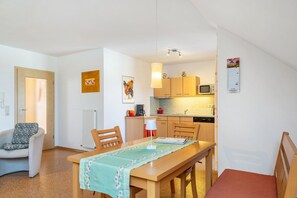 A compact living space with a dining area, kitchenette, and a single bed.