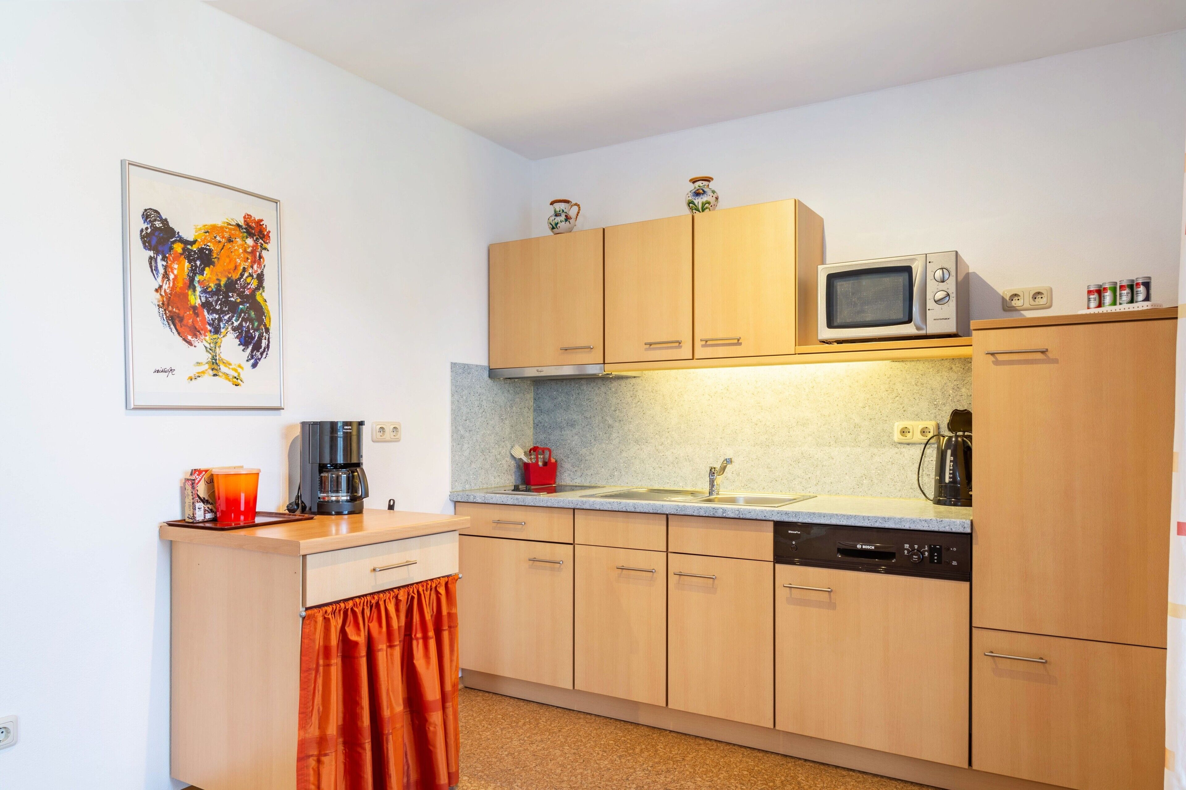 A compact kitchen with wooden cabinets, a microwave, a coffee maker, and a sink.