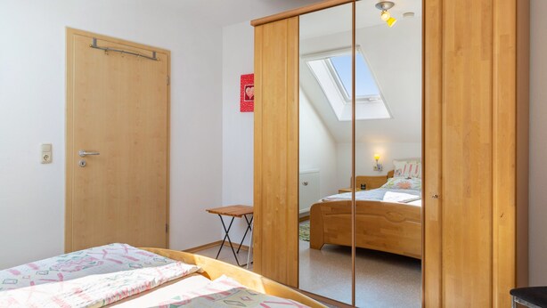 A bedroom with a bed, a small table, a wardrobe, a skylight, and a red sign on the wall. - Doppelhammer Apartment House (Bad Füssing)