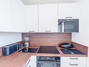 A modern kitchen with white cabinets, a built-in oven, a toaster, a blender, and a stovetop. - Apartment Joigny by Interhome (Arcachon)