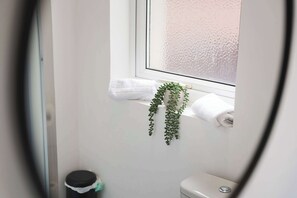 A bathroom with a toilet, a small trash bin, and a window with a frosted glass view. - Spacious 4BR Darlington Sleeps 8 by Stay with us (Darlington)