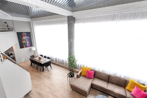 Una sala de estar moderna con comedor, un ventanal grande y una escalera.
