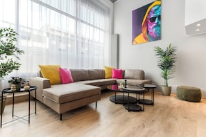 A modern living room with a sectional sofa, a coffee table, and a potted plant. - Loft 21 - Stylish Five Bedroom Apartment (Reykjavík)