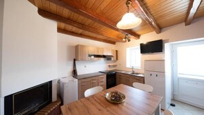 Una cocina con vigas de madera, una mesa de comedor y un televisor.