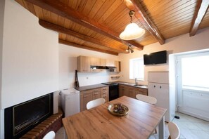 A kitchen with wooden beams, a dining table, and a TV. - Costas Vlachos Appartement (Corfu)