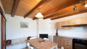Una cocina con armarios de madera, una mesa de comedor con sillas, una lámpara colgante y una estufa.