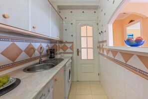 A narrow kitchen with a sink, a coffee maker, and a washing machine. - Beachfront Apartment with Sea Views in Tamarindos Benalmádena (Benalmádena)