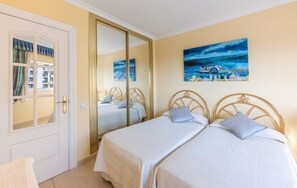A hotel room with a bed, a wardrobe, a mirror, and two paintings on the wall. - Beachfront Apartment with Sea Views in Tamarindos Benalmádena (Benalmádena)