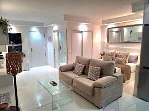 Un salon moderne avec un canapé, une table basse en verre et un téléviseur.