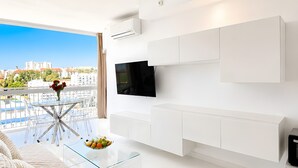A modern living room with a flat-screen TV, white cabinetry, a glass coffee table, and a sofa with patterned cushions. - Beachfront, 12th Floor with Stunning Views, Maite 2, Benalmádena (Benalmádena)