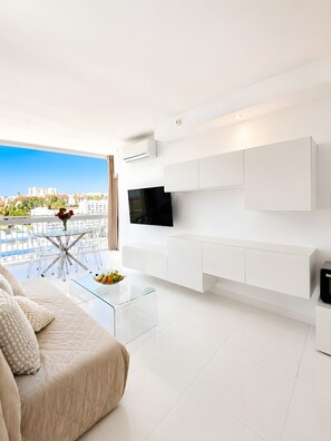A modern living room with a flat-screen TV, white cabinetry, a glass coffee table, and a sofa with patterned cushions. - Beachfront, 12th Floor with Stunning Views, Maite 2, Benalmádena (Benalmádena)
