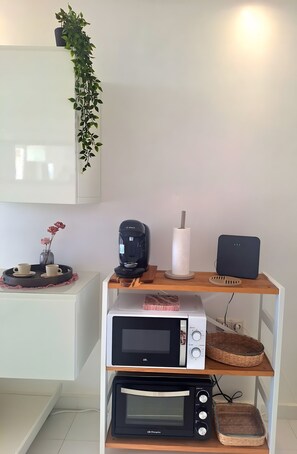Eine Küche mit Mikrowelle, Toaster und Kaffeemaschine auf einer Holzauslage, einer Topfpflanze und einer Blumenvase.