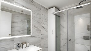 A modern bathroom with a marble backsplash, a large mirror, a glass-enclosed shower, and a white sink. - Beachfront, 12th Floor with Stunning Views, Maite 2, Benalmádena (Benalmádena)
